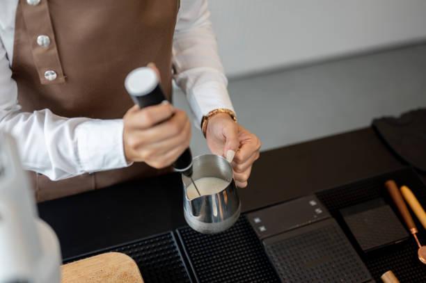 A barista using a milk frother