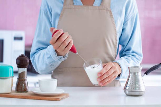 Woman making aromatic coffee with using a milk frother